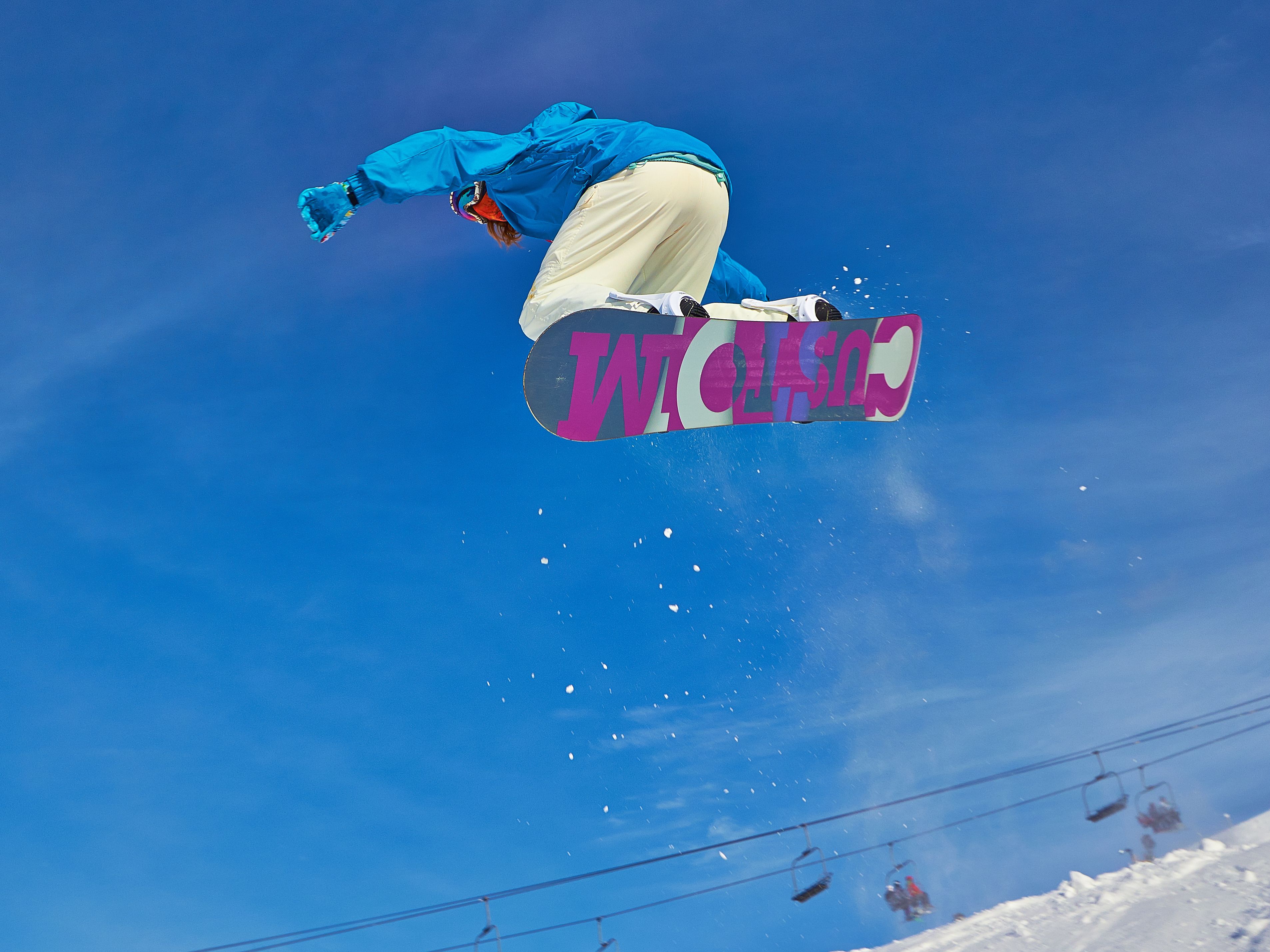 Um snowboarder no ar contra um céu azul límpido.