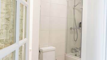 A bathroom with a toilet, shower, and a glass door leading to another room.