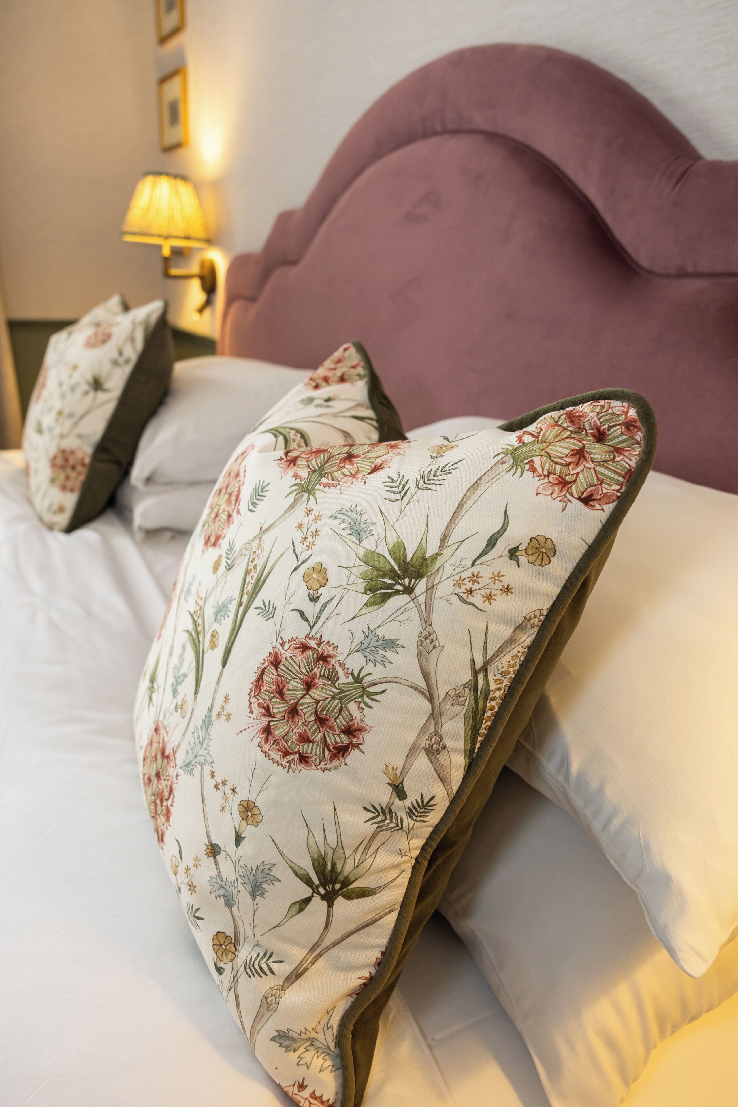 A bed with floral-patterned pillows and a headboard.