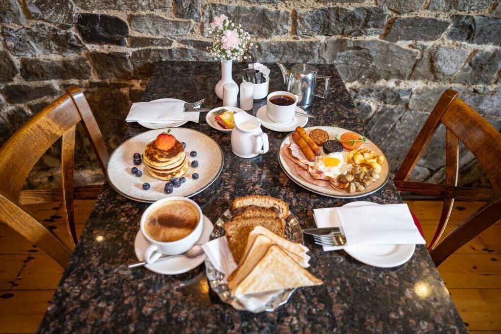 A breakfast table with plates of pancakes, eggs, toast, and coffee.