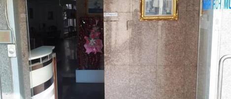 A building entrance with a glass door, a framed picture on the wall, and a banner above.
