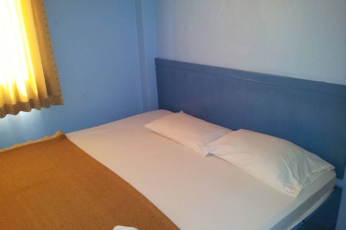 A single bed with white bedding in a room with blue walls and a wooden headboard.
