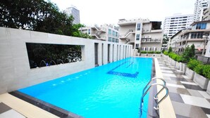 A swimming pool with a clear blue water feature, surrounded by a modern building with balconies and a checkered floor pattern. - Parinda Hotel (Bangkok)