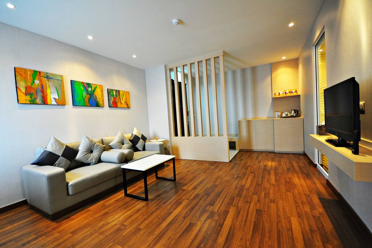 A modern living room with a sofa, coffee table, wooden flooring, and abstract art on the wall.