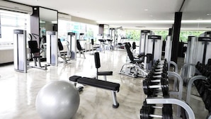A gym with various exercise machines, a bench, and dumbbells. - Parinda Hotel (Bangkok)