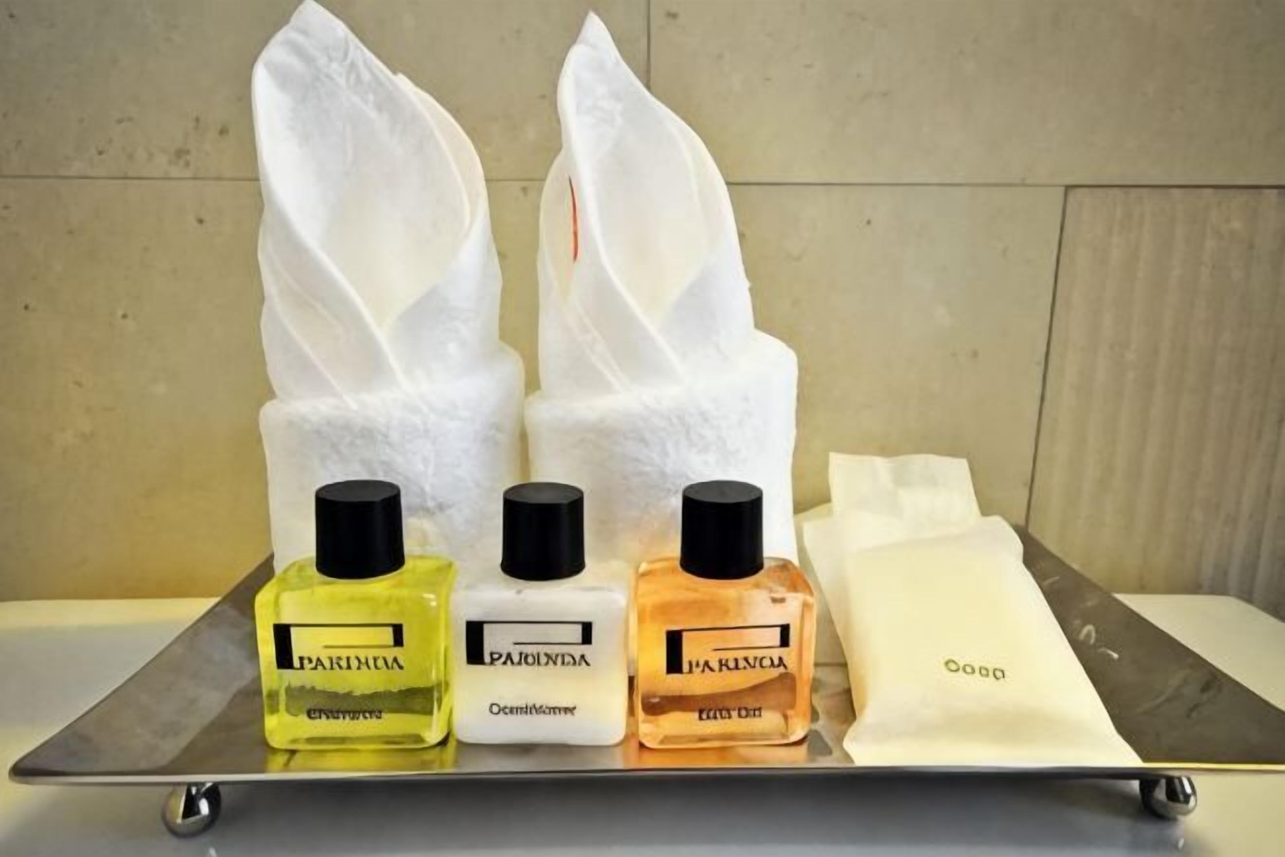 Een dienblad met drie flesjes Parfums de Parfums eau de cologne en twee pakjes witte zakdoekjes.