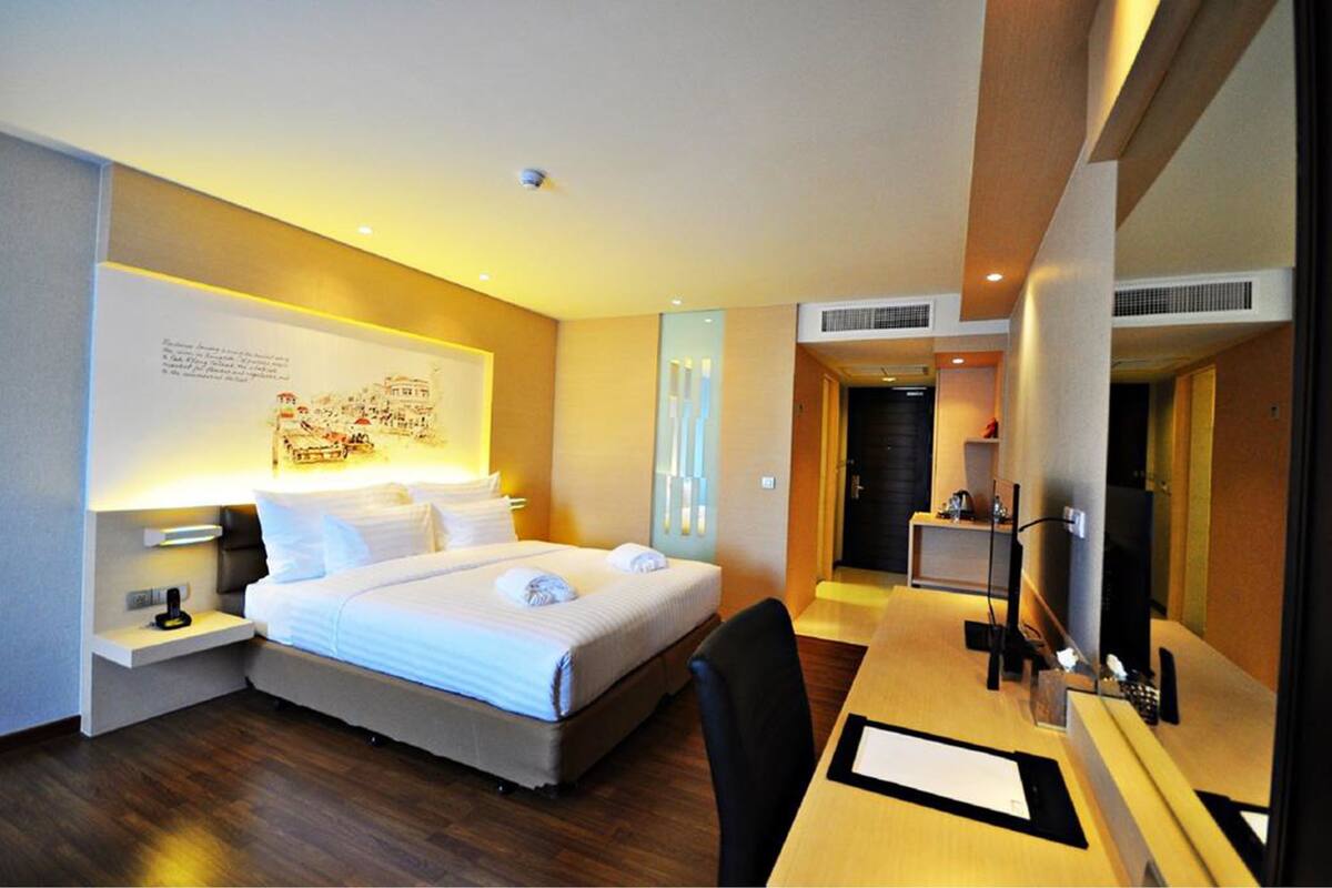 A hotel room with a bed, bedside tables, a desk, and a chair.