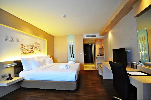 A hotel room with a large bed, a desk with a chair, a television, and a wall-mounted artwork. - Parinda Hotel (Bangkok)