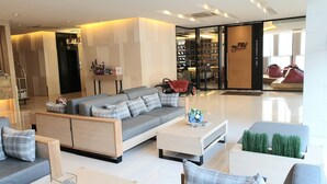 A modern hotel lobby with a grey sofa, a white coffee table, and a glass display case. - Parinda Hotel (Bangkok)