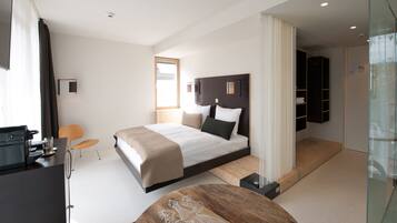 Une chambre d’hôtel moderne dotée d’un grand lit, d’un bureau, d’une chaise et d’une cabine de douche en verre.