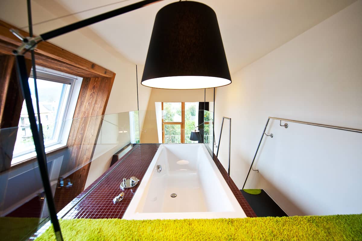 A modern bathroom with a large bathtub, a window, and a ceiling lamp.