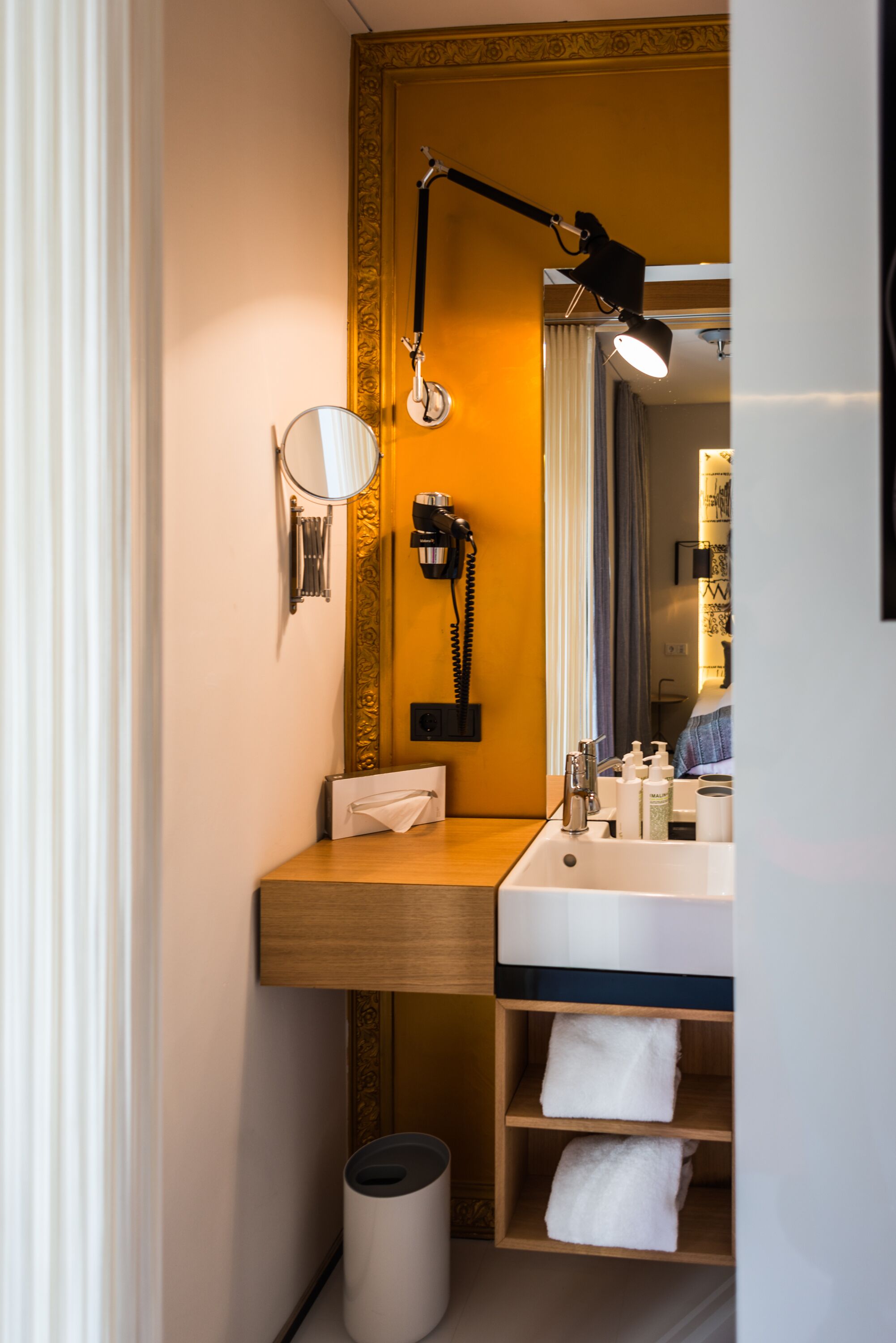 A compact bathroom with a wooden vanity, a mirror, a sink, and a towel rack.
