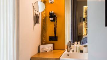 A compact bathroom with a wooden vanity, a mirror, a sink, and a towel rack.