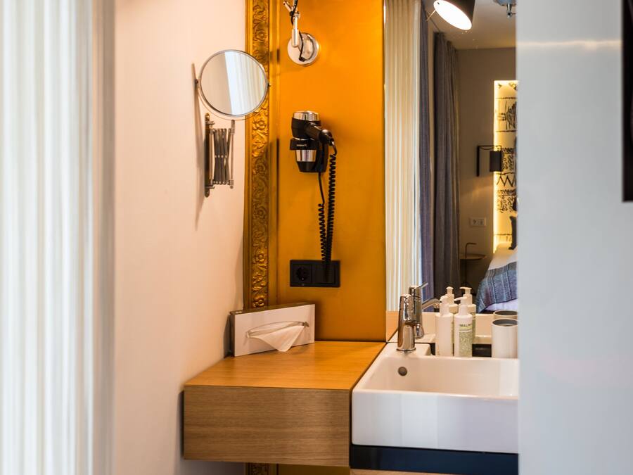 A compact bathroom with a wooden vanity, a mirror, a sink, and a towel rack.