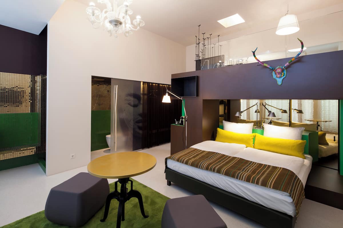 A modern hotel room with a large bed, a small table, and a unique ceiling decoration.