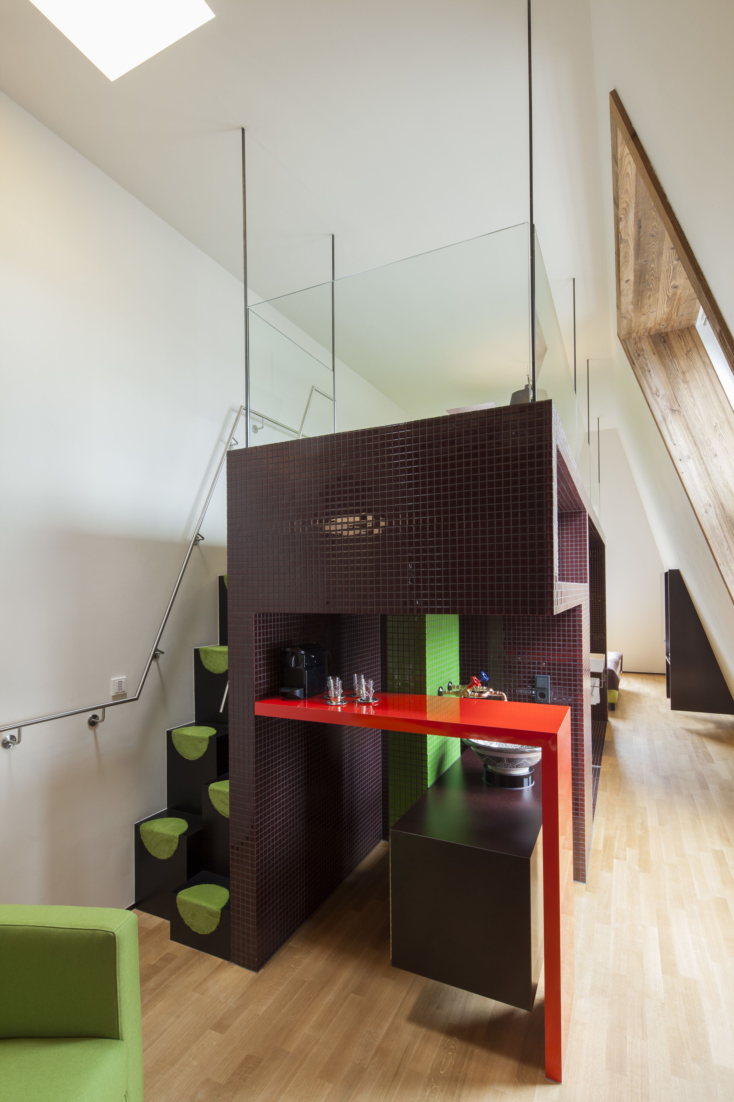 A modern kitchen with a red countertop, black cabinets, and a green chair.
