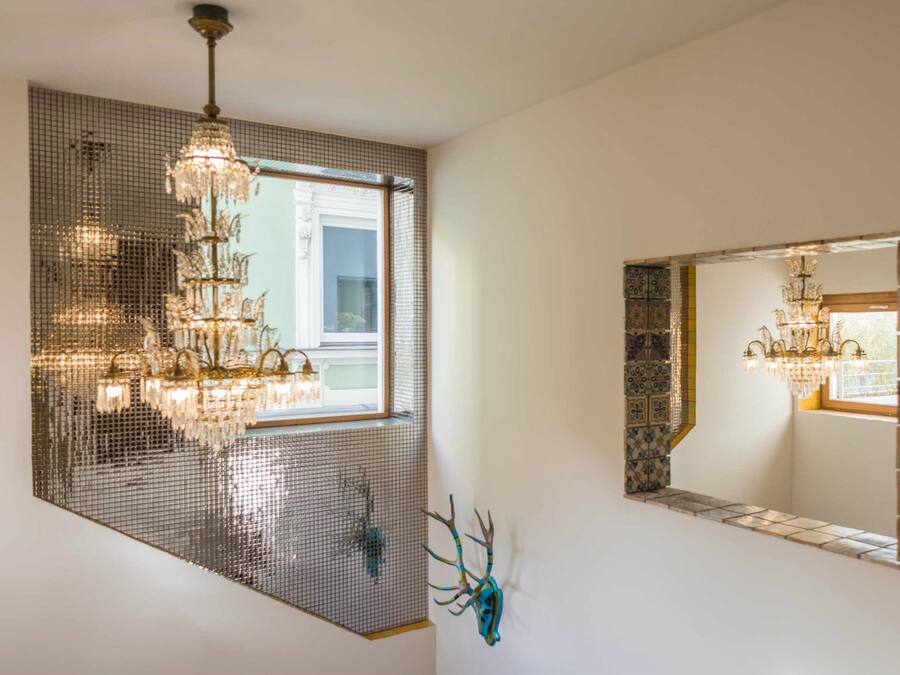 Een kamer met een groot raam, een kroonluchter en een decoratief wandobject.