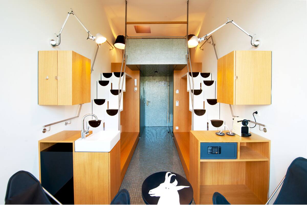 A narrow hallway with wooden cabinets, a desk with a computer, and two chairs.