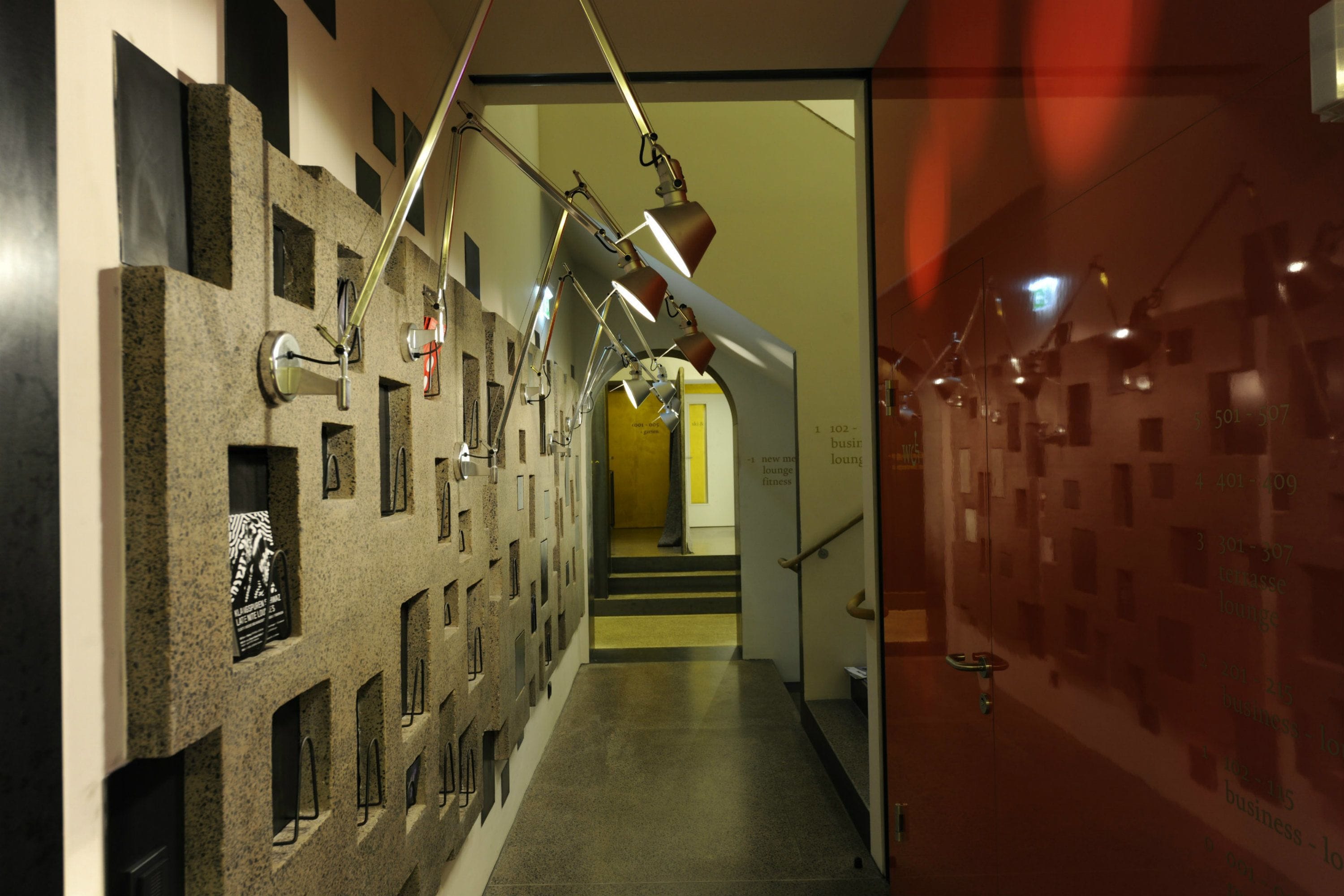 A hallway with lockers, a staircase, and a glass wall with text.