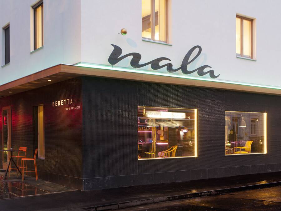 En modern byggnad med en skylt där det står ”nala” och en restaurang som heter ”Beretta Food Passion” på bottenvåningen.