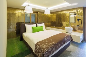 A hotel room with a large bed, a white sink, and a mirror. - NALA individuellhotel (Innsbruck)