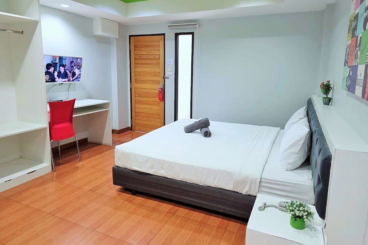 Une chambre d’hôtel moderne équipée d’un lit, d’un bureau, d’une chaise et d’un téléviseur.