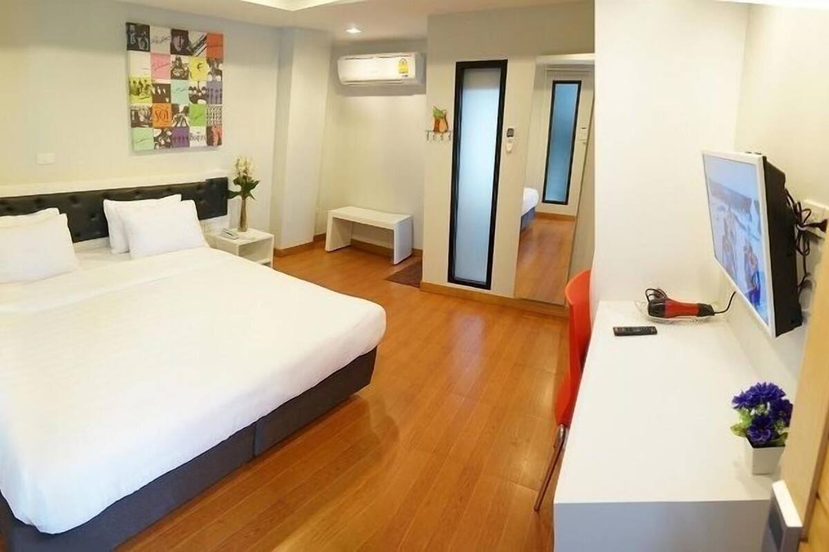 Une chambre d’hôtel dotée d’un grand lit, de tables de chevet, d’un bureau avec une chaise, d’un téléviseur à écran plat et d  ’un climatiseur fixé au mur.