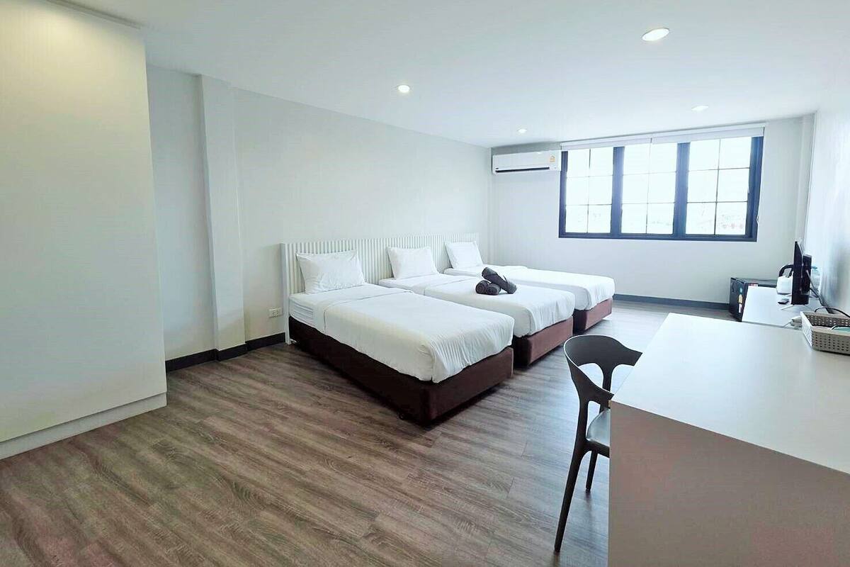 Une chambre d’hôtel moderne avec deux lits, un bureau et une chaise.