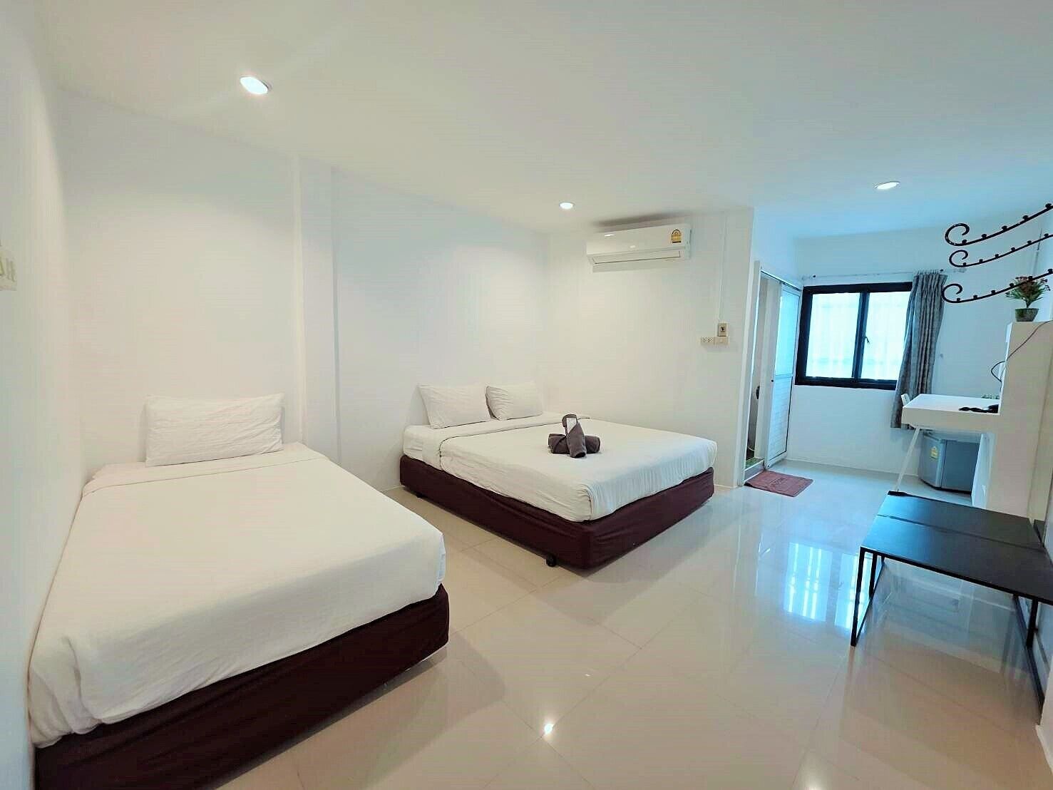 Habitación de hotel con dos camas, una mesita y una ventana.