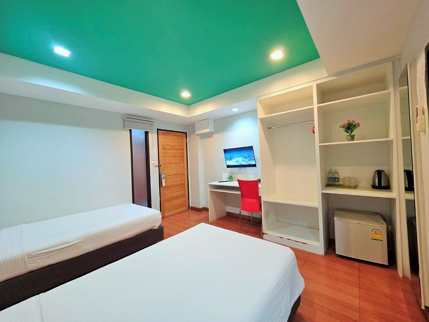 A hotel room with a bed, a desk, a chair, a wardrobe, and a television.