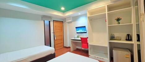 A hotel room with a bed, a desk, a chair, a wardrobe, and a television.