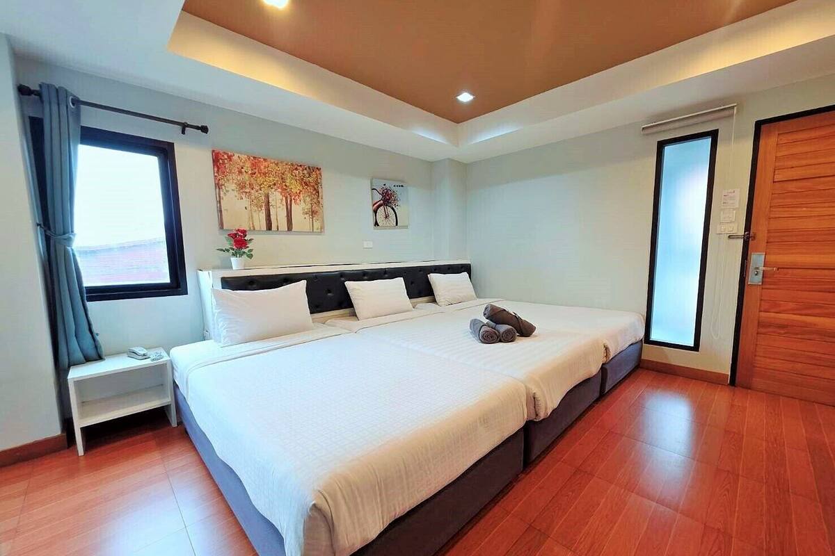 Une chambre d’hôtel moderne avec un grand lit, une table de chevet, une fenêtre avec des rideaux et une porte.