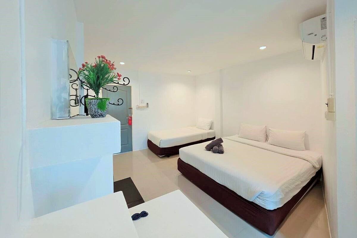Une chambre d’hôtel avec deux lits, une petite table et une plante en pot.