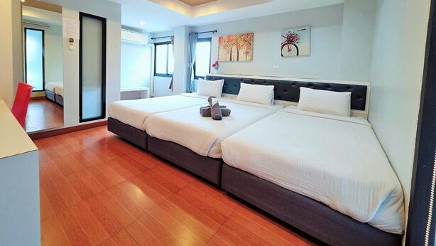 Een moderne hotelkamer met twee bedden, een houten vloer en uitzicht op de gang.