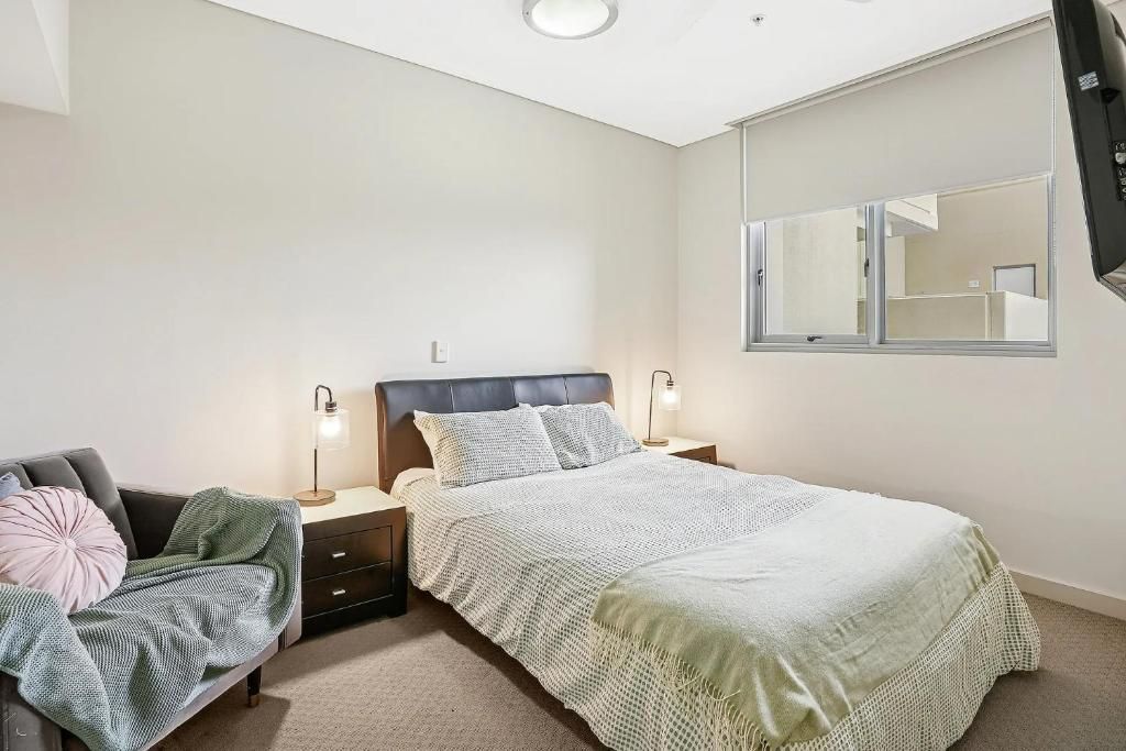 Une chambre à coucher avec un lit, des tables de chevet, une commode, une chaise et une fenêtre.