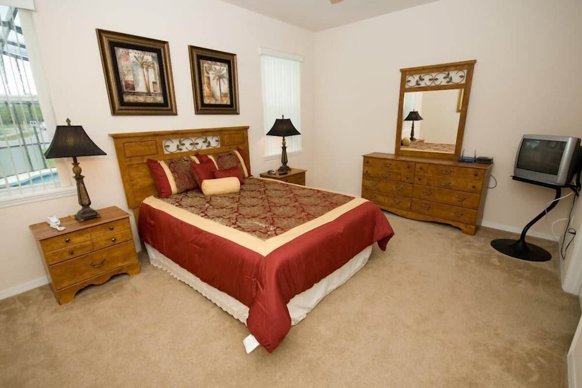 A bedroom with a large bed, two nightstands, a dresser, a mirror, and a television.