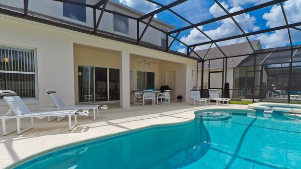 An indoor swimming pool with lounge chairs and a covered patio area.