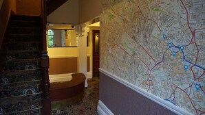 A staircase with a patterned carpet and a wall-mounted map. - The Boundary Hotel (Leeds)