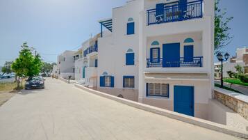 A street lined with white buildings with blue accents, featuring balconies and doors.