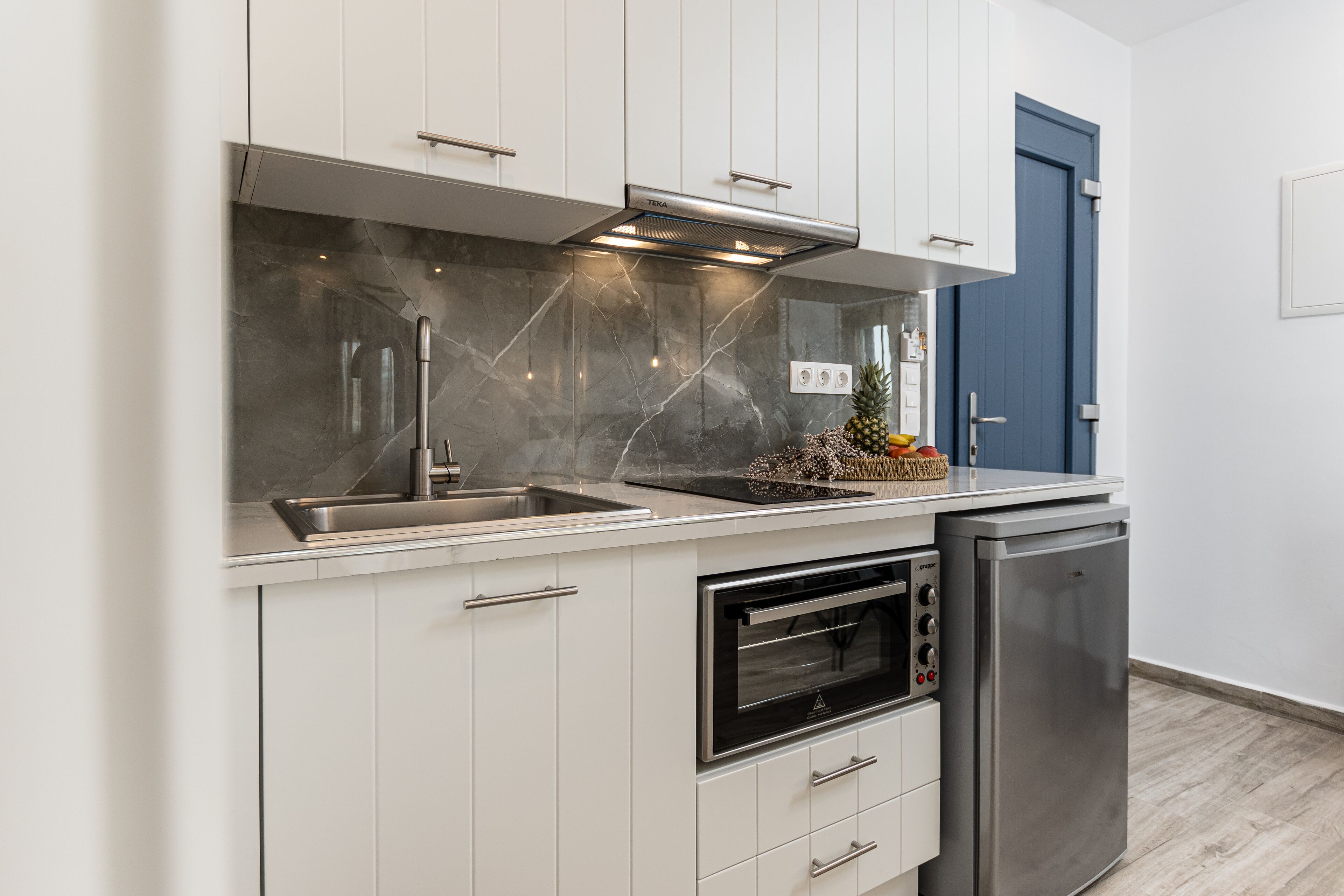 A modern kitchen with white cabinets, a stainless steel range hood, a built-in oven, and a dishwasher.