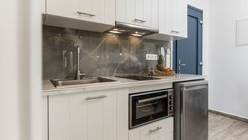 A modern kitchen with white cabinets, a stainless steel range hood, a built-in oven, and a dishwasher.