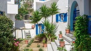 A courtyard with white buildings, blue doors, and potted plants. - Sun Beach Hotel (Naxos)