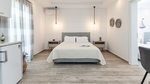 A modern bedroom with a large bed, bedside tables, a small desk, and a chair. - Sun Beach Hotel (Naxos)
