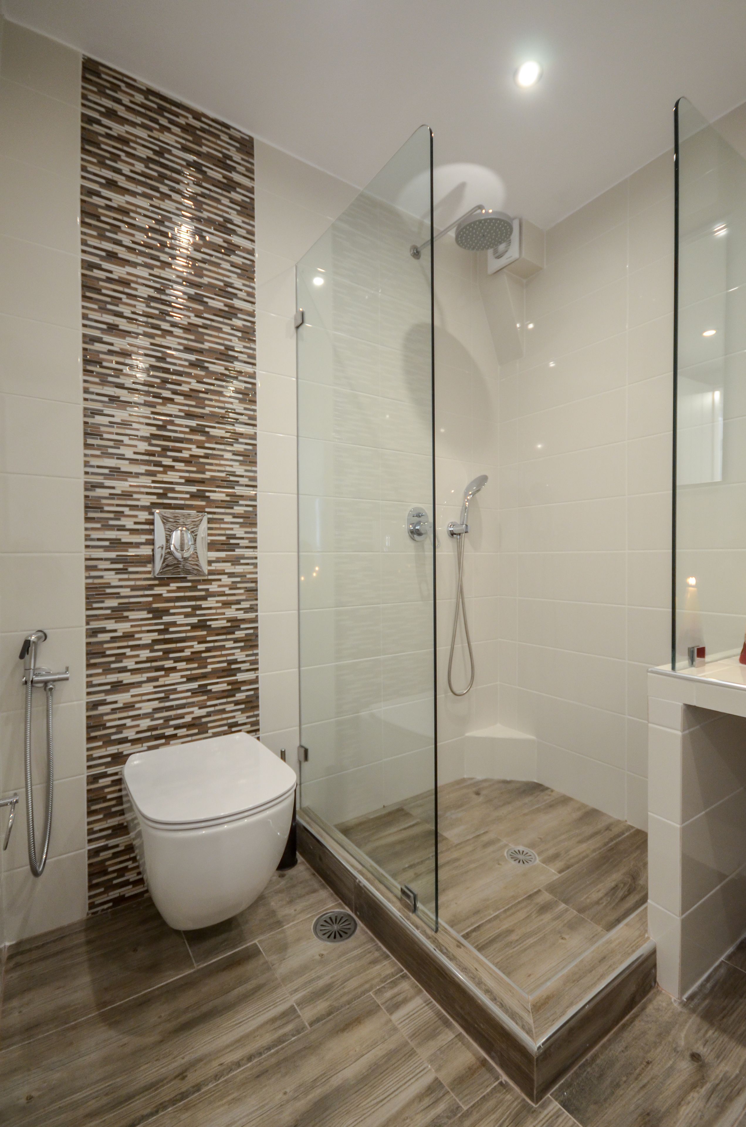 A modern bathroom with a glass-enclosed shower, a toilet, and a tiled wall with a wood-like pattern.