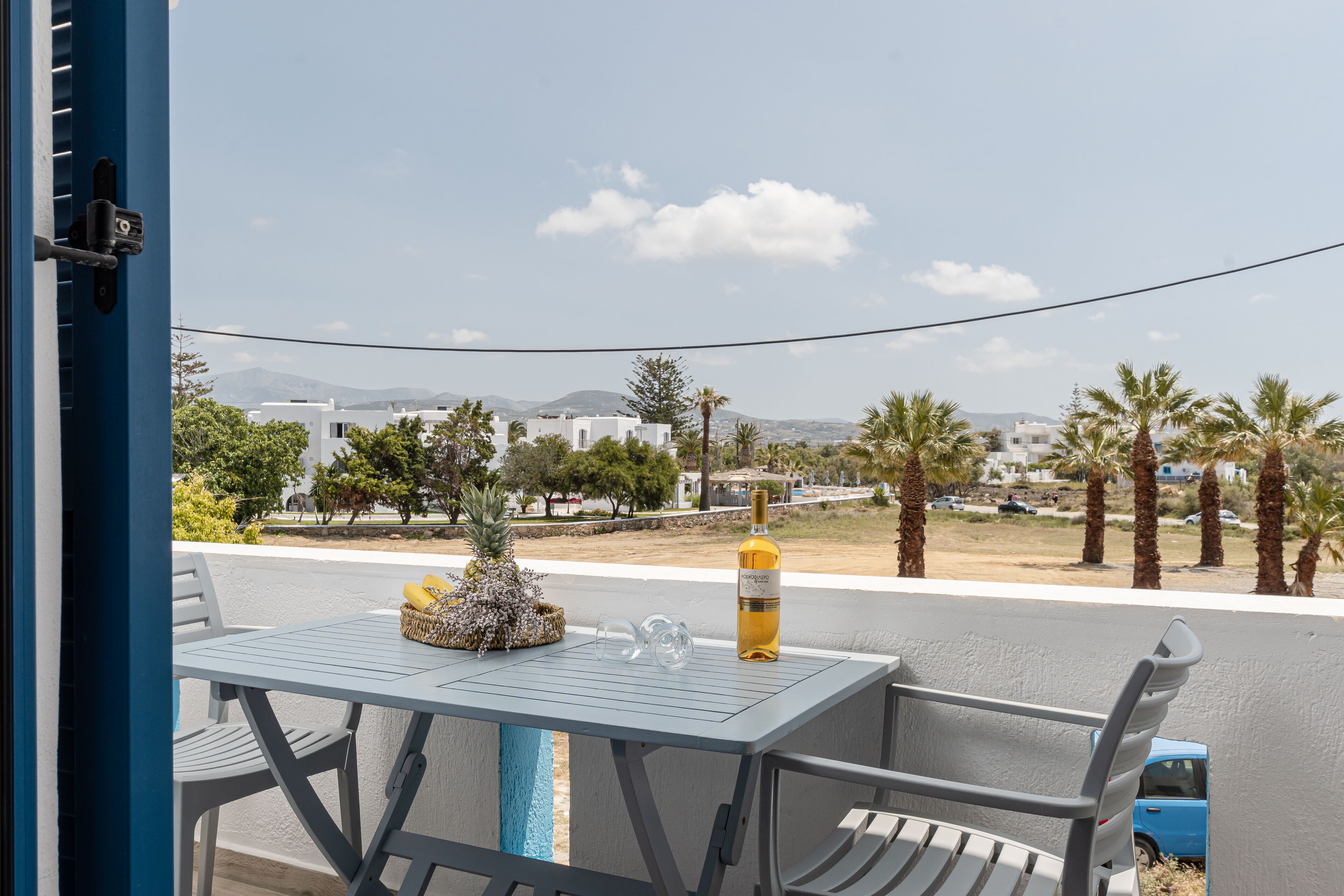 Ein Balkon mit Tisch, Stühlen, einer Weinflasche und einer Ananas.