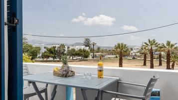 Ein Balkon mit Tisch, Stühlen, einer Weinflasche und einer Ananas.