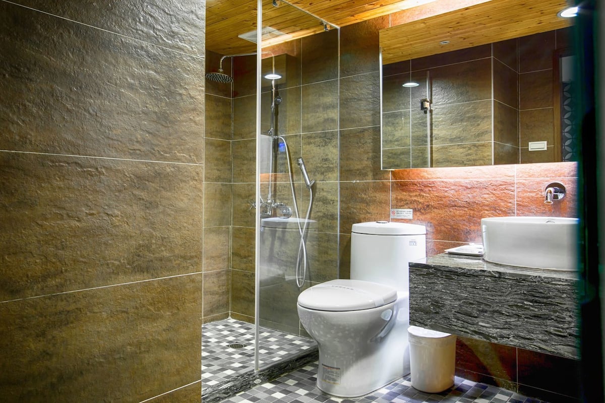 A modern bathroom with a glass-enclosed shower, a toilet, and a sink.