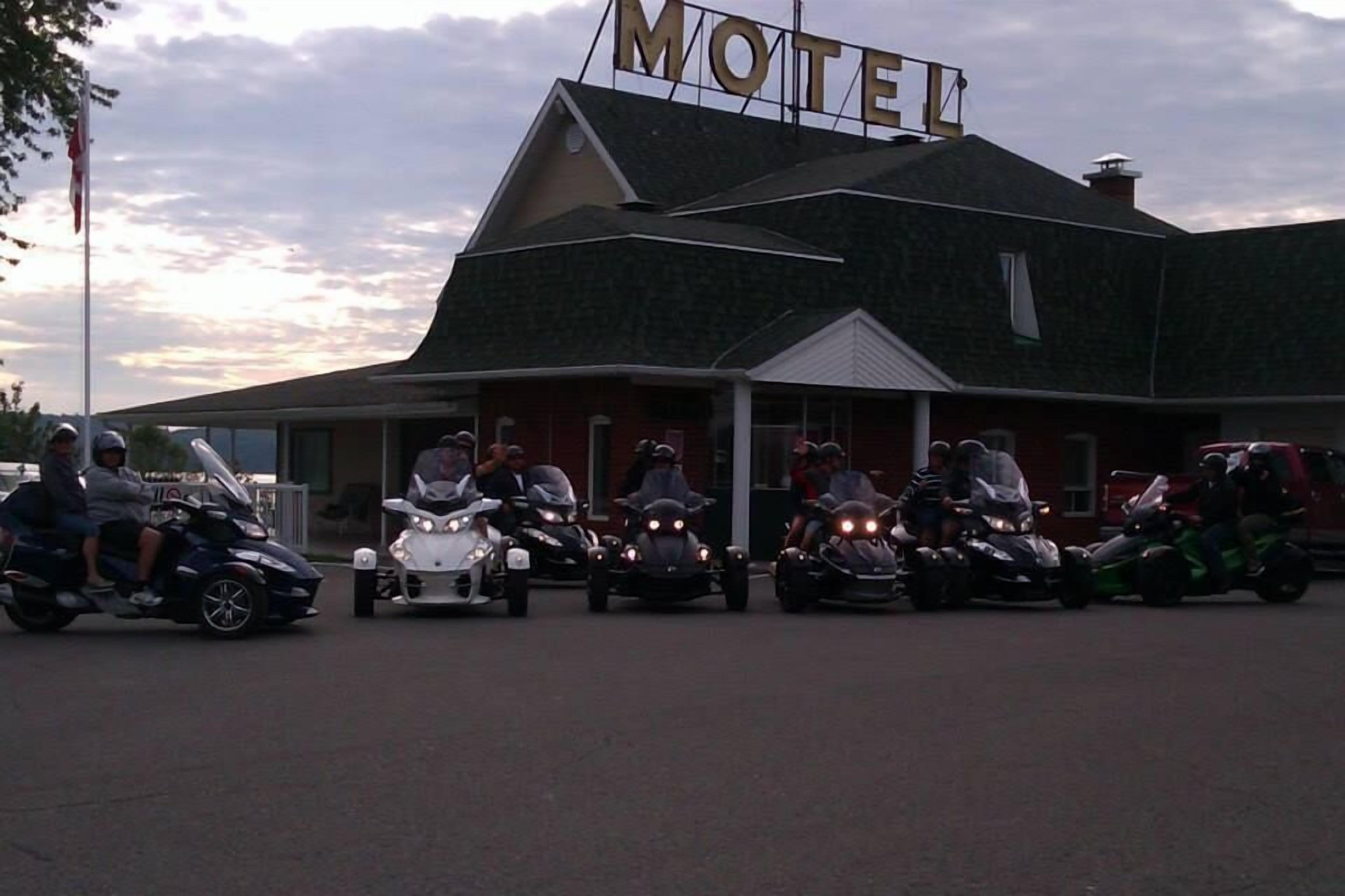 Un motel avec une grande enseigne, plusieurs motos garées devant et un mât sur lequel flotte un drapeau.