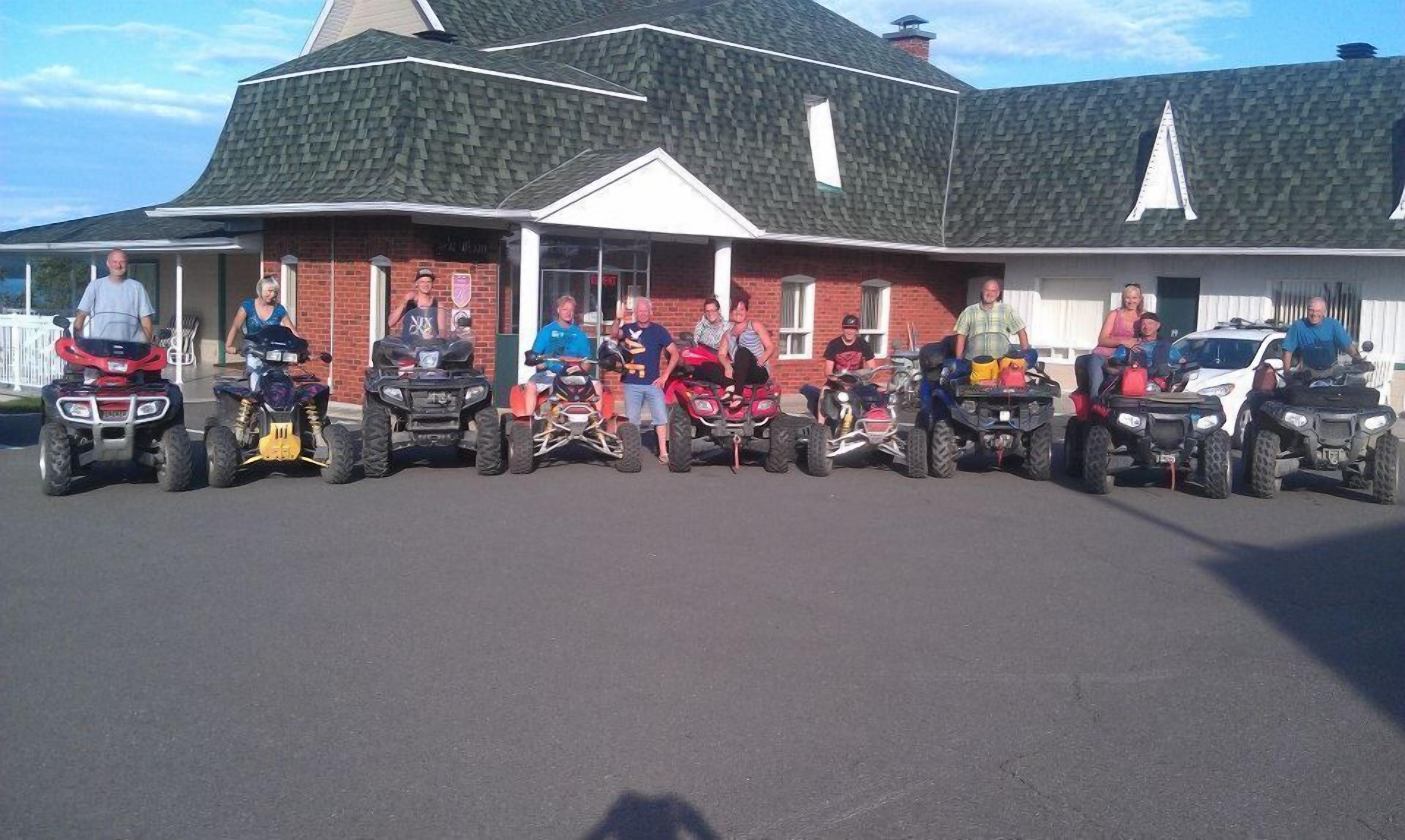 A row of ATVs parked in front of a building with a steeply pitched roof and a brick facade.