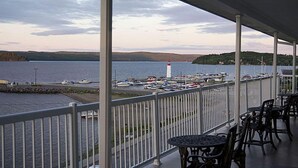 A covered outdoor area with a view of a harbor, including boats and a lighthouse. - Motel Royal (Temiscouata-sur-le-Lac)
